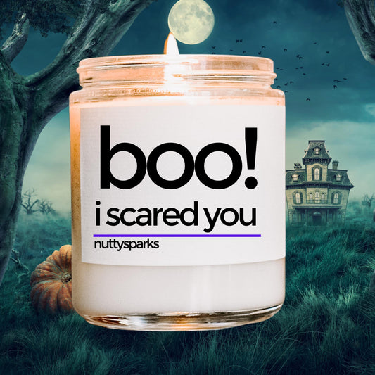 a candle with a house in the background that says boo i scared you